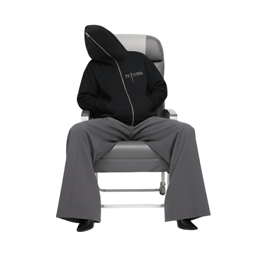 Vicki Holland wearing a ATELIER FULL-ZIP BOXY HOODIE gray Maison Margiela pants sitting on a gray commercial airline chair